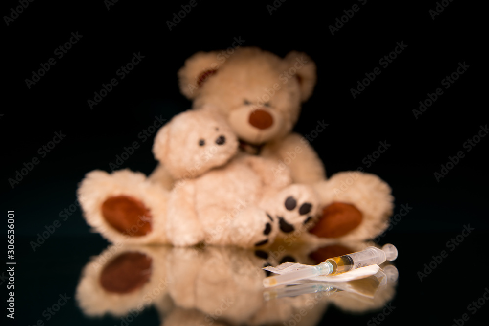 Fototapeta premium syringe with a dose of drugs and teddy bears in defocus