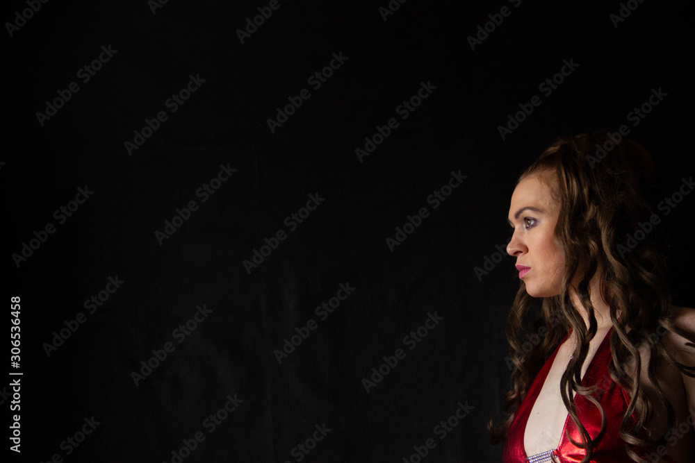 Naklejka premium portrait of a sexy girl with long hair in a short dress with an open back on a black background