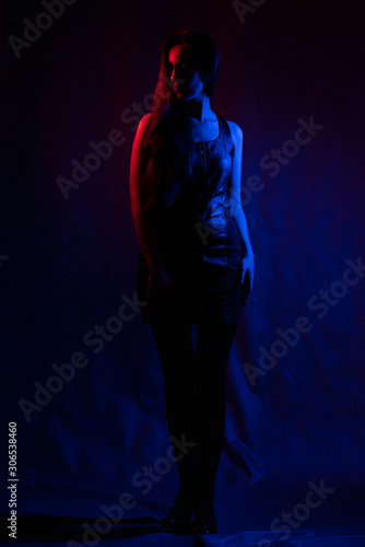 portrait of a girl in the dark. silhouette of a girl in the light of colored lamps in red and blue.