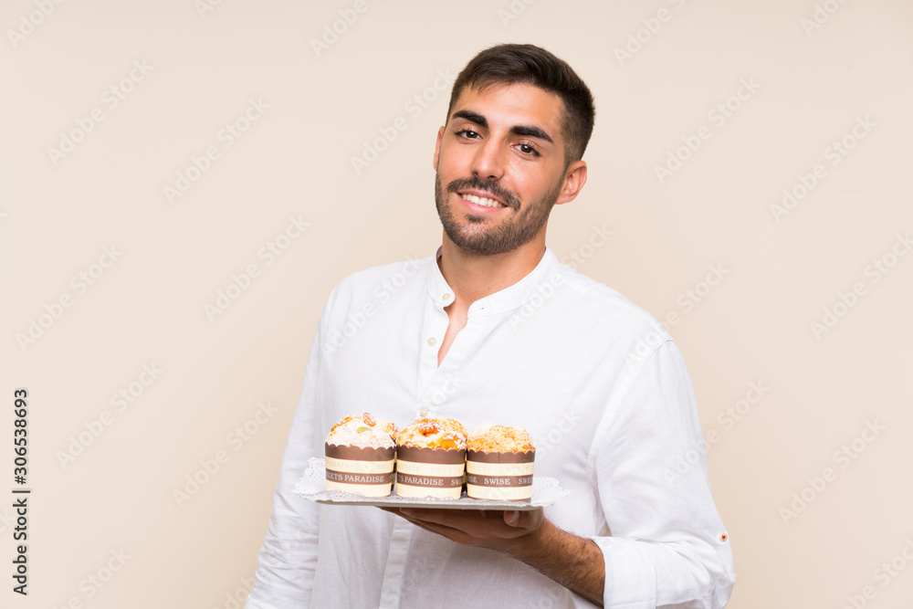 Handsome man holding muffin cake over isolated background