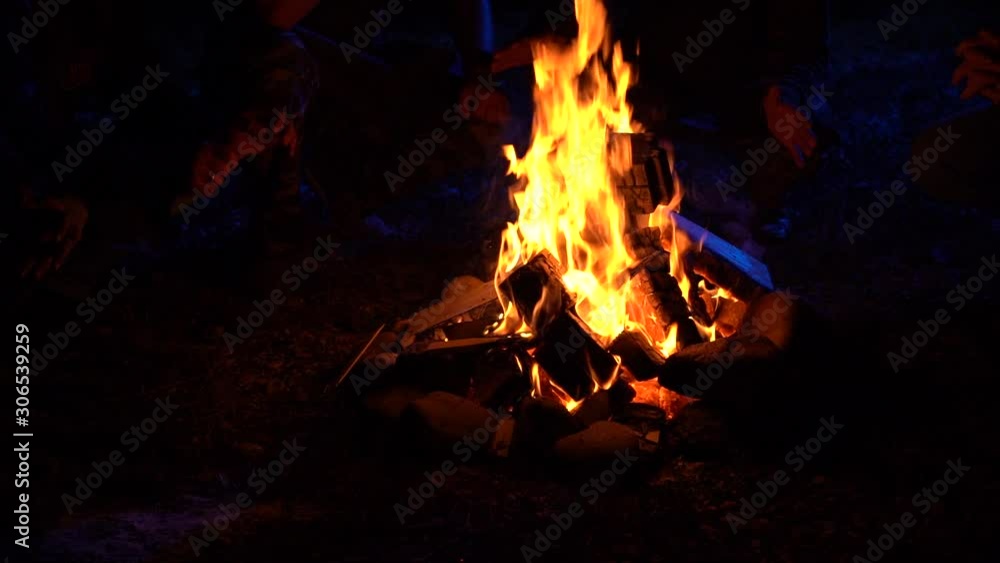 Four men sit near the fire at night in moonlight warm their hands and tell scary stories 100 fps Slow Motion Four men sit near the fire at night in moonlight warm their hands and tell scary stories 100 fps Slow Motion