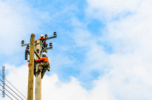 Electricians are climbing on electric poles to install and repair power lines.
