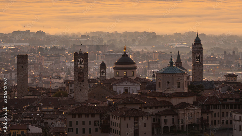 Bergamo, one of the most beautiful city in Italy. Amazing landscape at the old town during the sunrise. The fog covers the plain around the town. Fall season. Warm colors contest