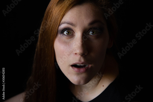 portrait of a young woman on a black background. Surprise on the face. female emotions
