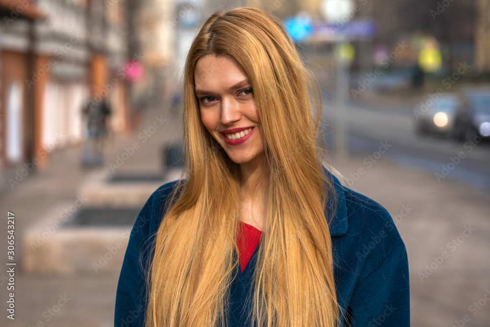 Young beautiful blonde woman in a blue coat
