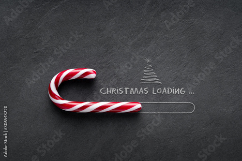 Christmas loading Concept - Candy cane on blackboard with christmas tree