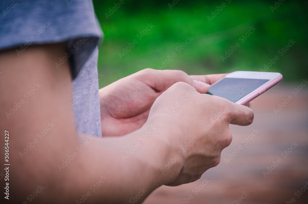 Close-up of a man's hand is holding mobile phone with copy space screen against blurred jungle landscape.