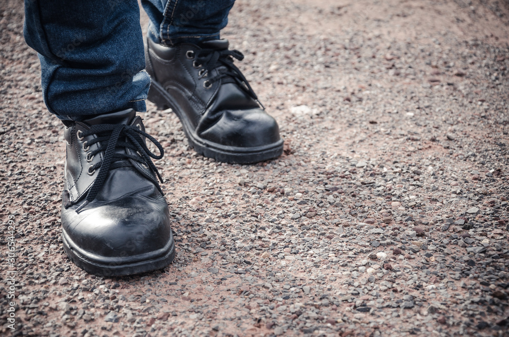 Man wearing safety shoes black color, standing on the ground