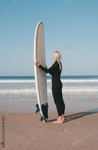 A girl staying with a surfboard on the beach of the Atlantic ocean Peniche Portugal