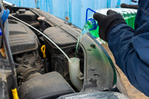 the driver pours the seasonal washer fluid into the tank