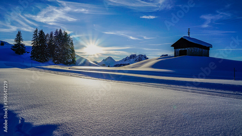 paysage enneigé avec des montagnes pointues dans le fond soleil et ciel bleu et traces dans la haute neige dans les préalpes suisses