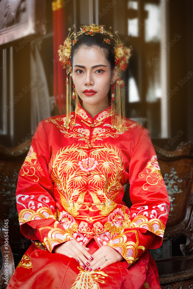Asian woman in red traditional chiness dress sit on wooden bench,opera chinese.