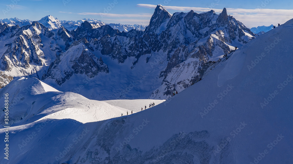 Cordée d'alpinistes au Mont-Blanc dans un décors enneigé avec des montagnes dans le fond