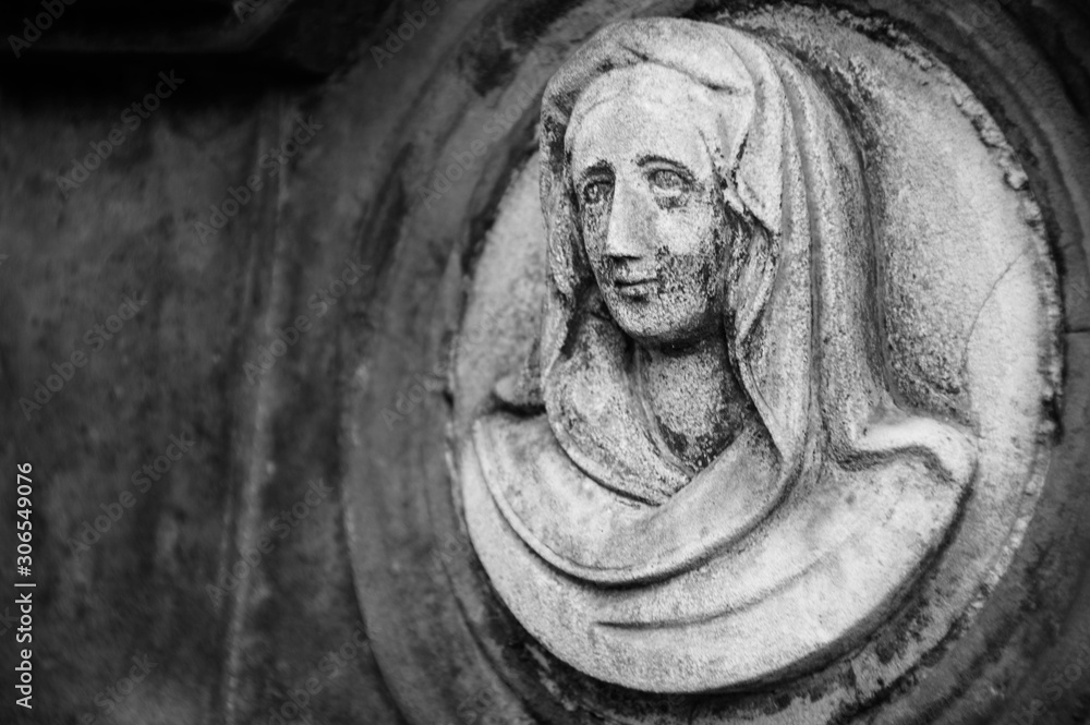 Fototapeta premium Monument and candles in the cemetery. All Saints Day in Poland. Stone sculpture. Stone angel.