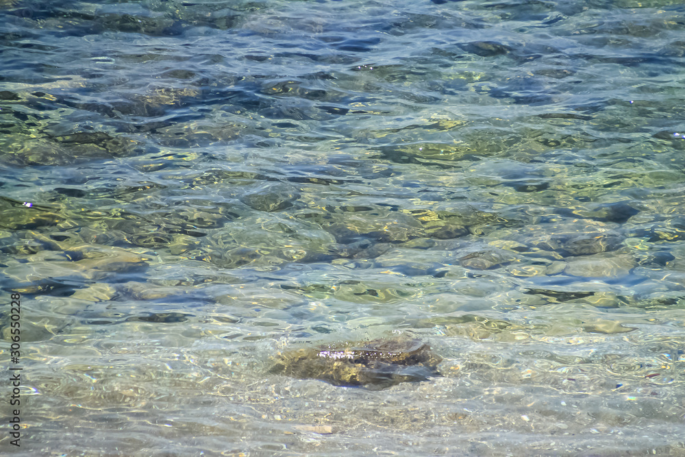 View of the clear waters of the Mediterranean Sea as small ripple waves roll over the rocks and sand under the surface