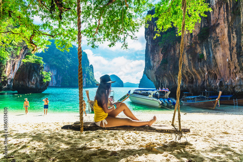 Traveler woman in bikini sitting on swing using tablet on tropical beach Lao Lading island Krabi, Leisure tourist travel Phuket Thailand Summer holiday vacation, Tourism beautiful destination Asia