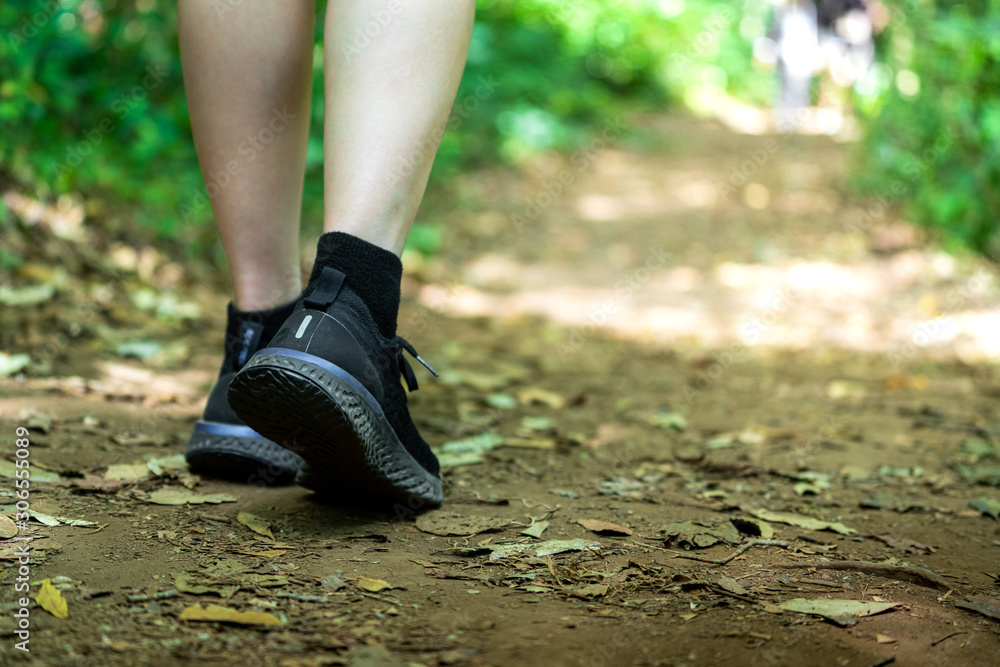 Adventure in the jungle / recreation activity concept background. Close up focus at the people foot during walking on the dirt route in tropical jungle.