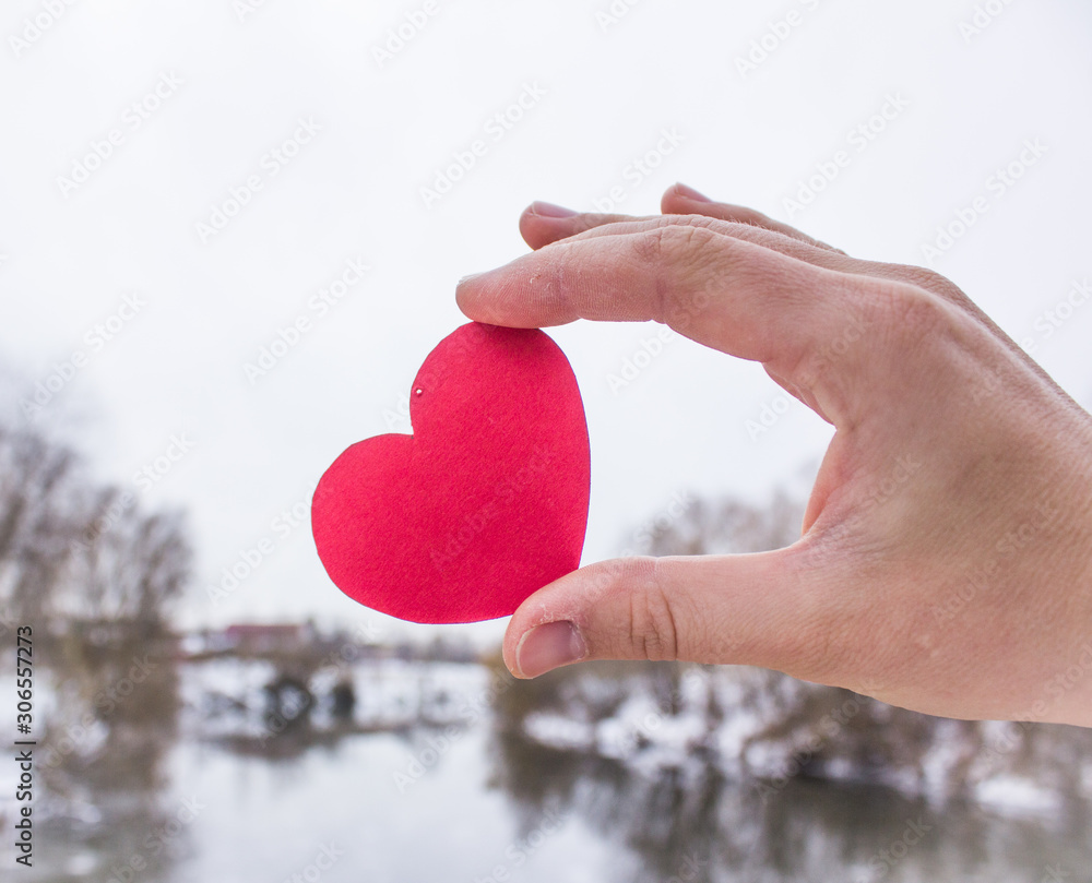 red heart in the hand of the girl. background river. St. Valentine's Day. Valentine's Day postcard. Love concept for mother's day with space for text red heart in the hand of the girl. background river. St. Valentine's Day. Valentine's Day postcard. Love concept for mother's day with space for text