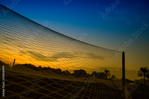 The net texture over colorful sunrise sky in the farm in selective focus with sihlouette trees background. photo