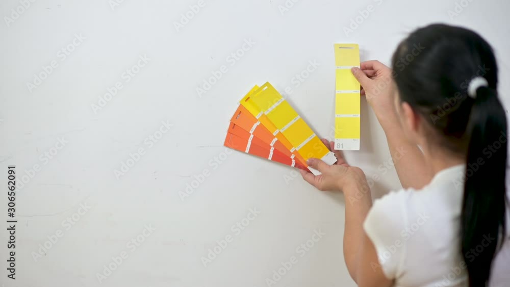 Woman designer standing near the wall chooses a color for painting. Design and interior. Home repairs Woman designer standing near the wall chooses a color for painting. Design and interior. Home repairs