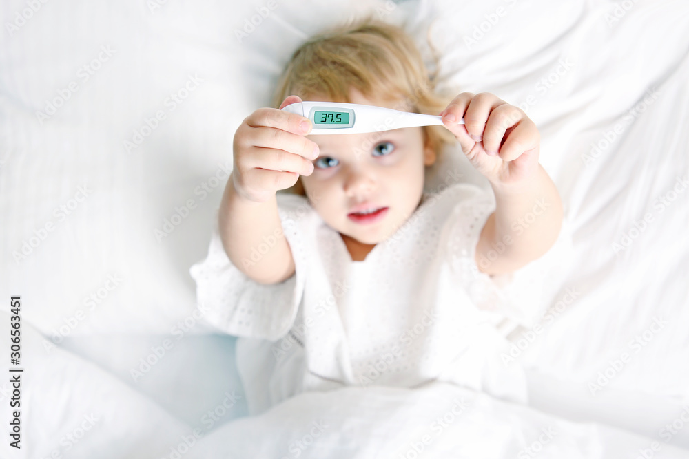 Fototapeta premium Caucasian child girl in bed with thermometer,ill kid with temperature. fever