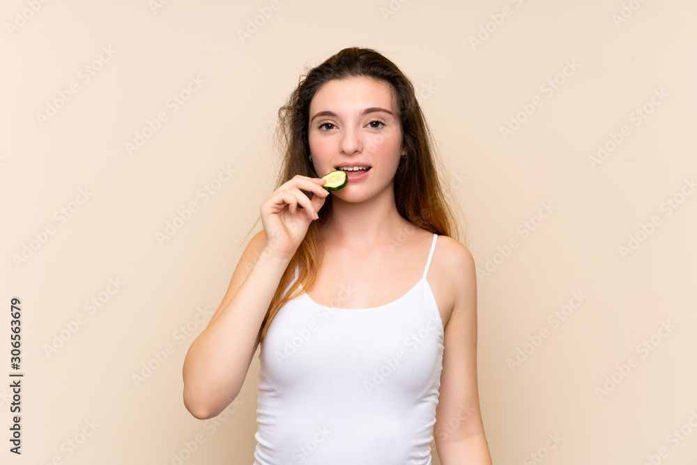 Young brunette girl holding slices of cucumber over isolated background Young brunette girl holding slices of cucumber over isolated background