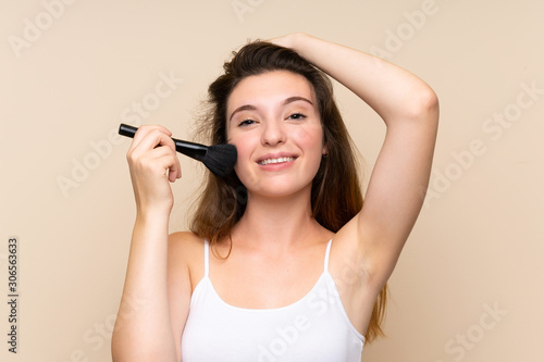 Young brunette girl with makeup brush over isolated background