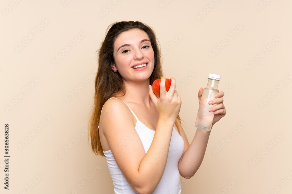 Young brunette girl with an apple and with a bottle of water over isolated background Young brunette girl with an apple and with a bottle of water over isolated background
