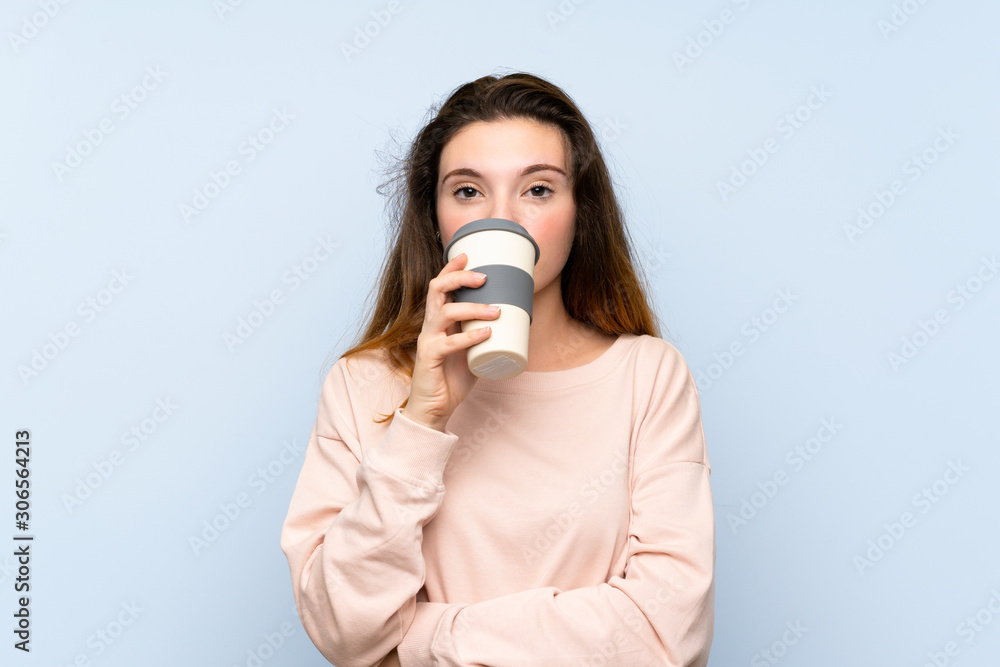 Young brunette girl over isolated blue background holding and drinking a coffee to take away Young brunette girl over isolated blue background holding and drinking a coffee to take away