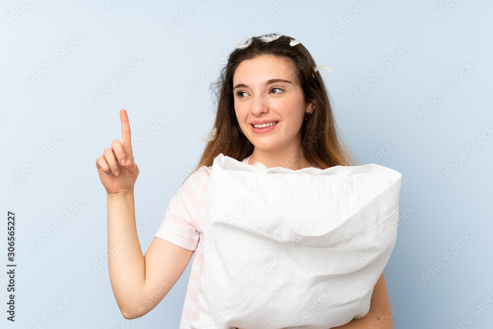 Young woman in pajamas over isolated blue background intending to realizes the solution while lifting a finger up Young woman in pajamas over isolated blue background intending to realizes the solution while lifting a finger up