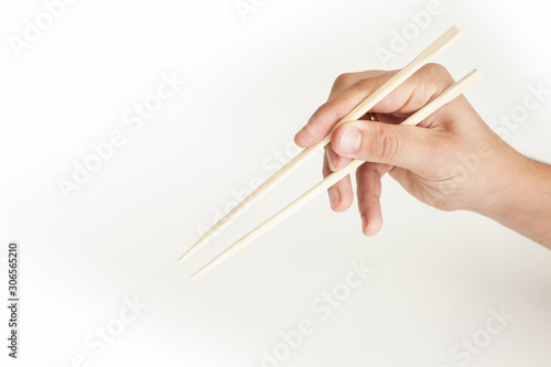 Hand on a white background holds sushi sticks