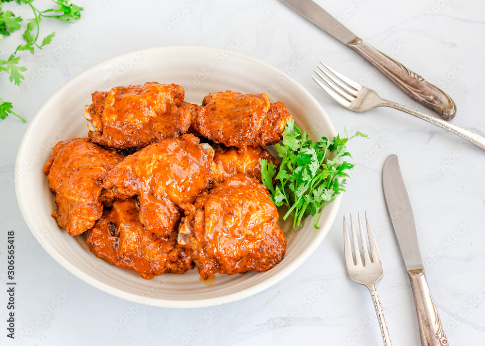 Baked Chicken Thighs Tossed in Buffalo Sauce, White Background Baked Chicken Thighs Tossed in Buffalo Sauce, White Background
