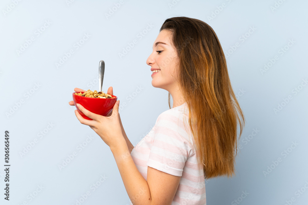Young brunette girl holding a bowl of cereals over isolated background Young brunette girl holding a bowl of cereals over isolated background