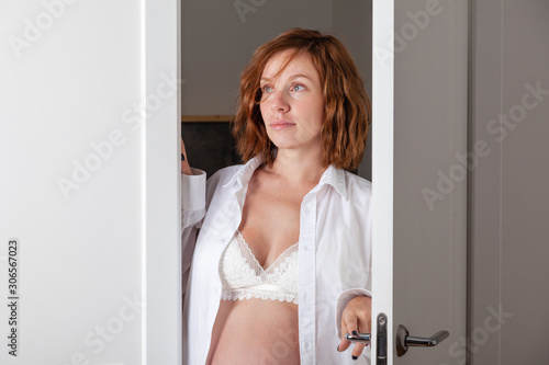 Caucasian Future mum - woman comes out of toilet. Beautiful portrait pregnant brunette in lingerie. Girl dressed in a white shirt  lace underwear