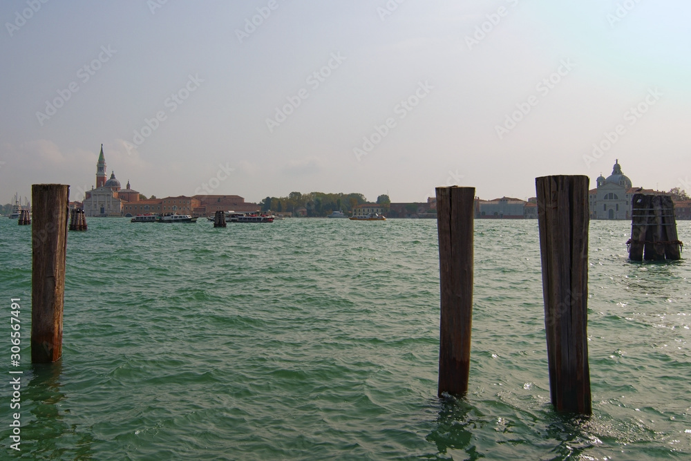 Picturesque city landscape of Venice at sunny autumn day. Wooden mooring poles in the Venetian Lagoon. The lagoon and a part of the city are listed as a UNESCO World Heritage Site. Venice, Italy