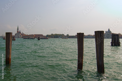 Picturesque city landscape of Venice at sunny autumn day. Wooden mooring poles in the Venetian Lagoon. The lagoon and a part of the city are listed as a UNESCO World Heritage Site. Venice, Italy