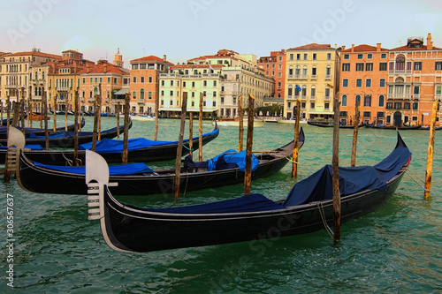 Venice, Italy-September 28, 2019: Classic landscape of Venice. Old black gondolas moored near wooden mooring poles. Scenic Grand Canal with turquoise water with ancient colorful buildings © evgenij84