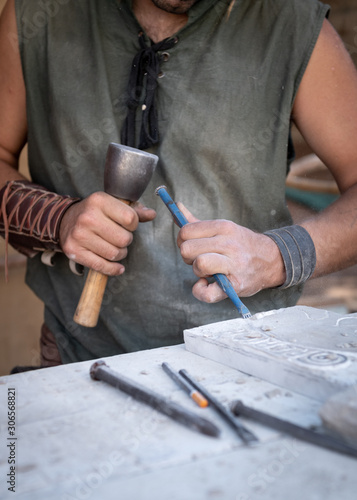 man's hands working with hammer and chisel in craft workshop.