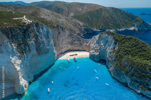 Aerial drone shot of Zakynthos Navagio beach with tourists with cruise ship in blue Ionnian sea