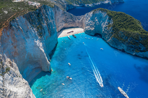 Aerial drone shot of Zakynthos Navagio beach with tourists with cruise ship in blue Ionnian sea photo