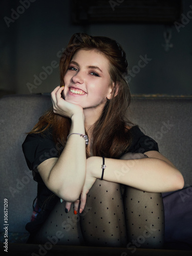 Portrait of a cute pretty redhead woman sitting in a cafe enjoying free time coffee break еhoughtfully looking into camera hugging knees