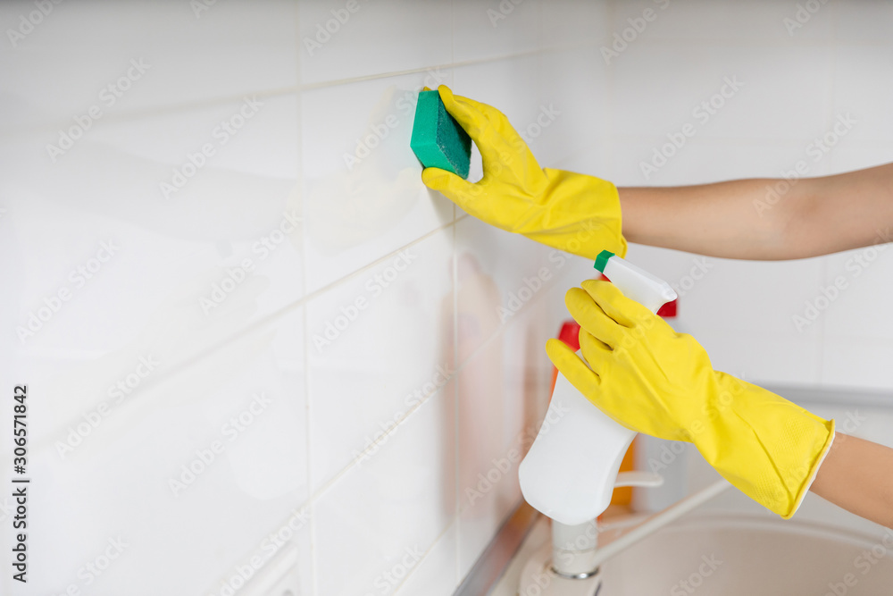 Woman cleaning and polishing the kitchen worktop with a spray detergent, housekeeping and hygiene concept