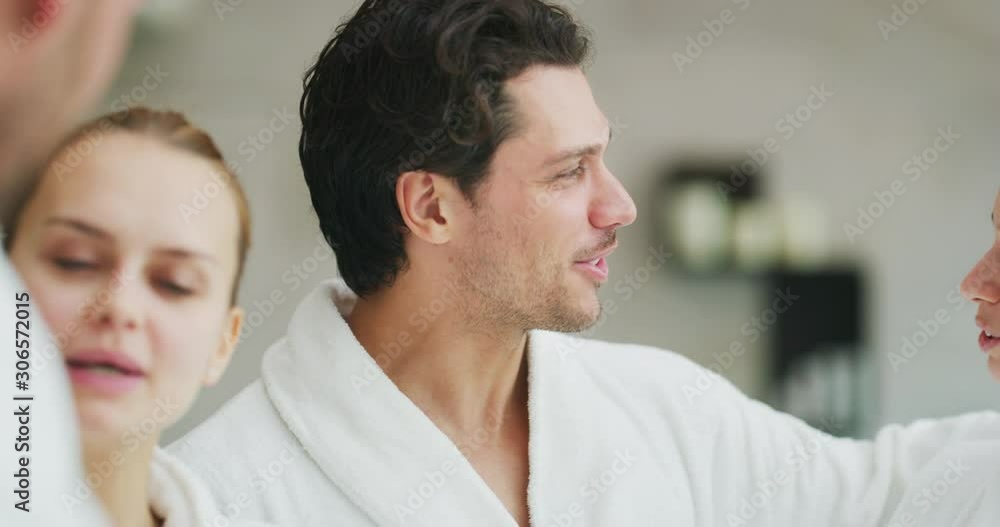 The young happy couples in white bathrobes are having fun together after various treatments in a luxury wellness center. The young happy couples in white bathrobes are having fun together after various treatments in a luxury wellness center.