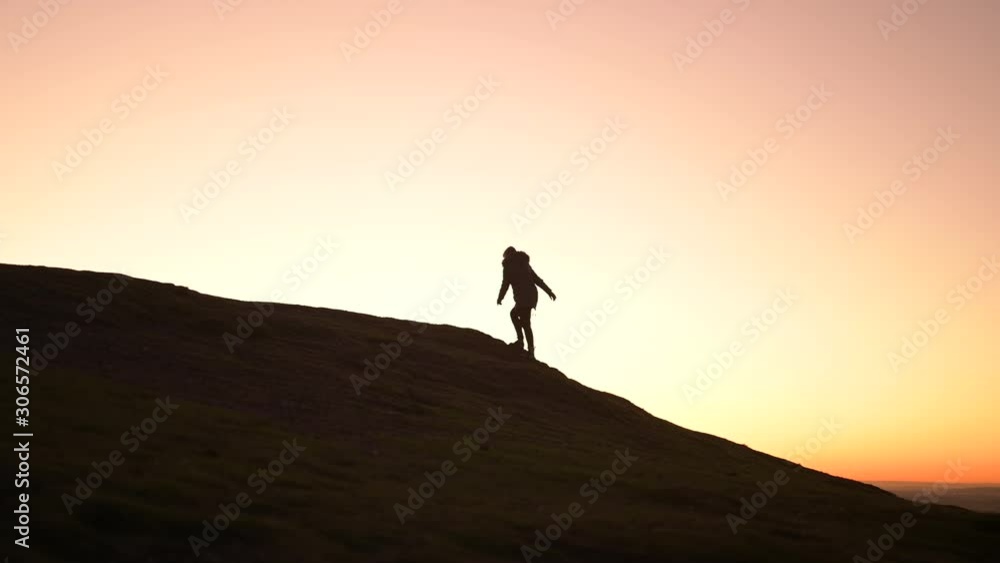 Silhouette of a hiker walking or climbing alone up the mountain or a hill at sunset. Journey and destination to the top. Silhouette of a hiker walking or climbing alone up the mountain or a hill at sunset. Journey and destination to the top.