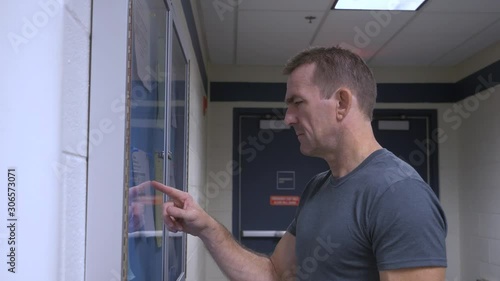 Man checking schedule, room for his class, bulletin board postings for schedules.