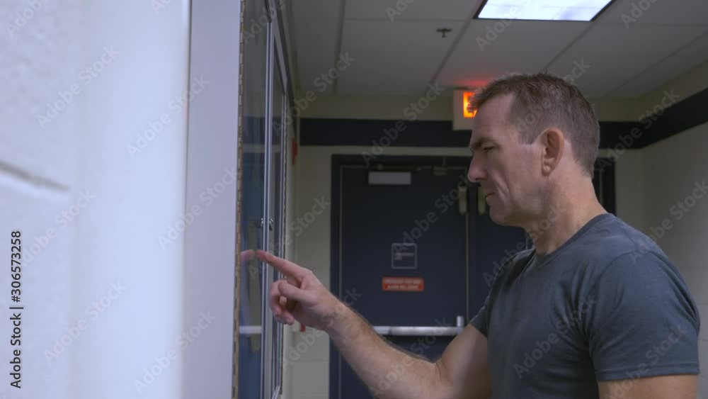 Man standing checking bulletin board for schedules and looking at what time and room his appointment is in. Man standing checking bulletin board for schedules and looking at what time and room his appointment is in.