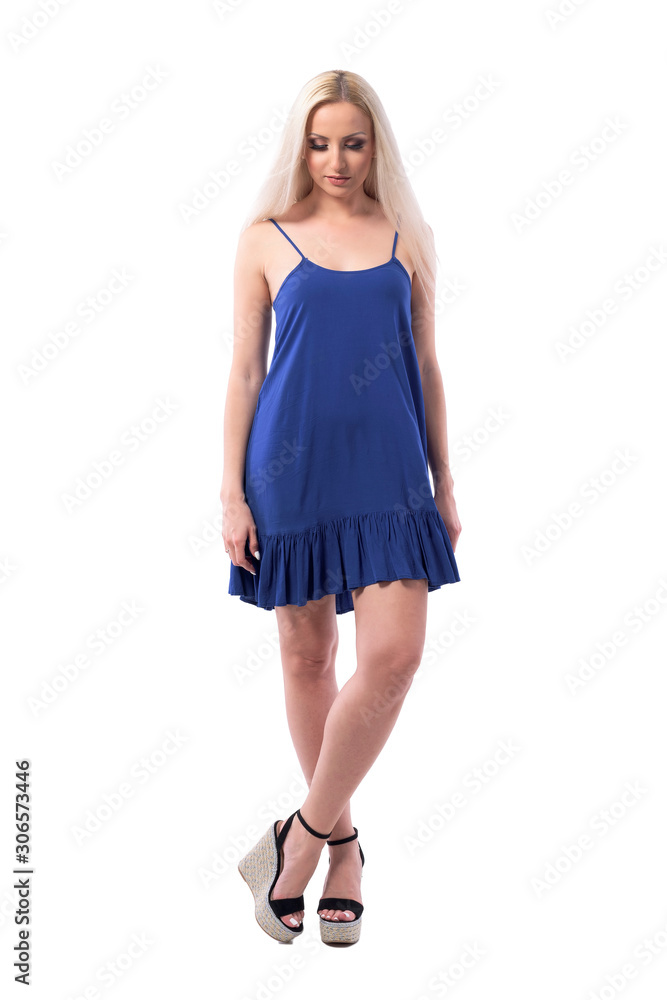 Naklejka premium Pretty blonde girl in elegant summer dress looking down smiling and having happy thoughts. Full body isolated on white background. 
