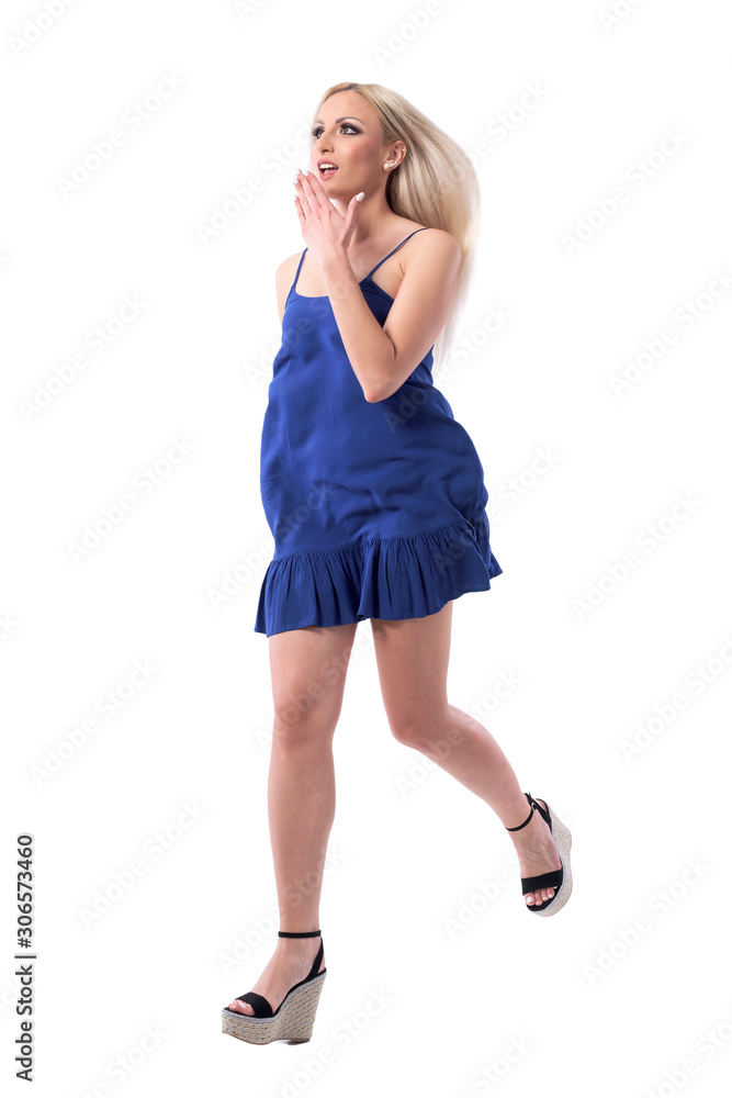 Shocked young blonde woman shopper running and looking up with surprised expression. Full body isolated on white background. 