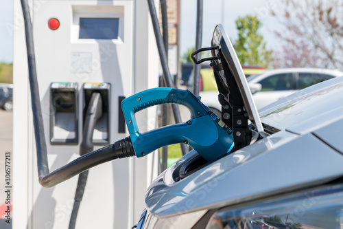 Electric car plugged in to charge battery at a charging station