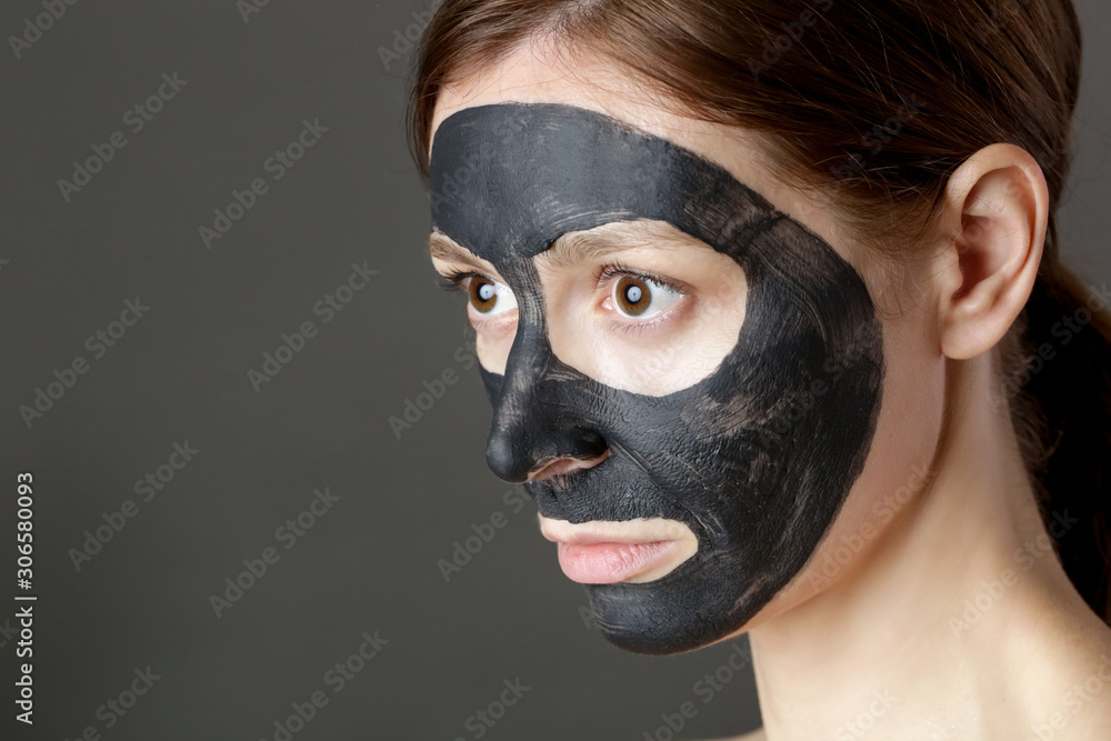 Charcoal face mask or black clay mud. Beautiful woman with black mask on her face, close up studio head shot. Natural cosmetic concept. Charcoal face mask or black clay mud. Beautiful woman with black mask on her face, close up studio head shot. Natural cosmetic concept.
